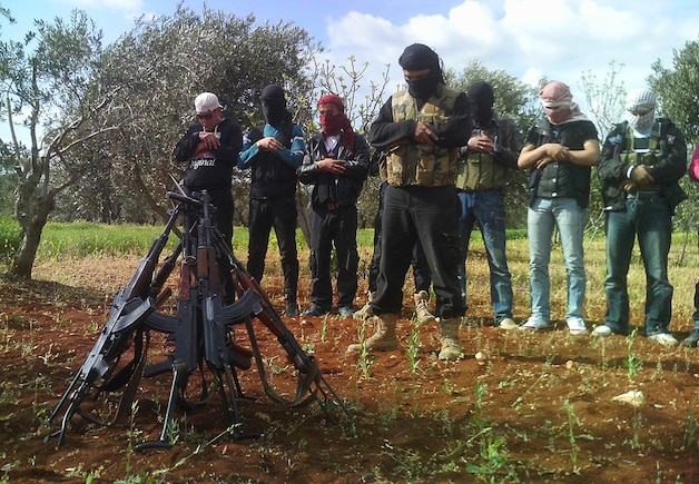 Leden van het Syrische verzet bidden naast hun wapens.