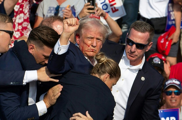 Donald Trump wordt van het podium geleid met bloed op zijn gezicht, na een aanslag in Butler, Pennsylvania op 13 juli 2024.