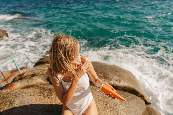 Beeld ter illustratie. Vrouw die zich insmeert met zonnecrème voordat ze de zee ingaat. 