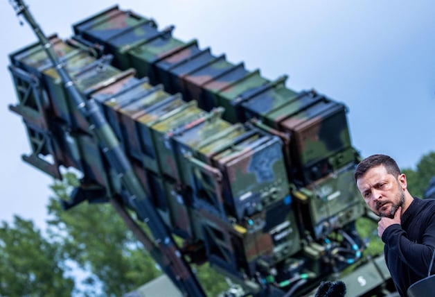 Ukrainian President Volodymyr Zelensky with a Patriot air defense system in the background. 