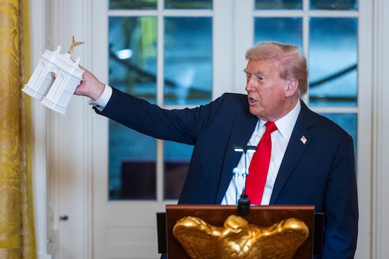 De Amerikaanse president Donald Trump toont een model van de triomfboog die zijn regering moet gaan bouwen in Washington D.C.
