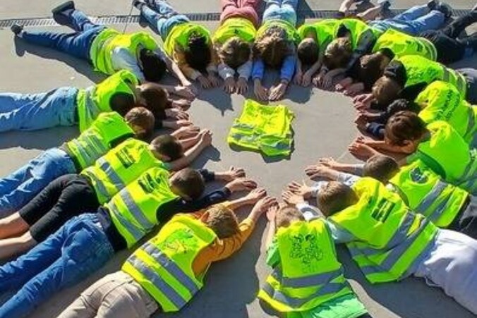 De leerlingen van het vierde leerjaar van GBS De Leerplaneet in Adinkerke vormen een hartje met hun armen.