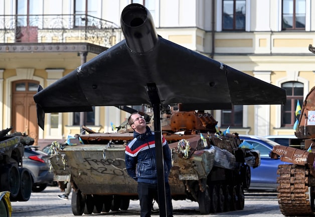 Archiefbeeld. An Oekraïense man got a deels vernield Shahed-drone on a square in Kiev waar various buitgemaakt Russians voertuigen en wagens staan.
