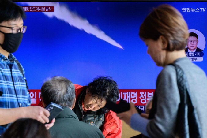 Voorbijgangers in een station in Seoul passeren een tv-scherm dat archiefbeelden uitzendt van een Noord-Koreaanse rakettest.