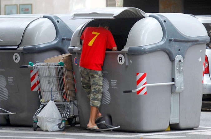 Een jongeman speurt naar etensresten in afvalcontainer in Bilbao.