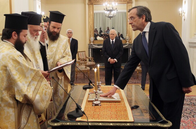 Antonis Samaras wordt ingezworen door de aartsbisschop van Athene. President Papoulias kijkt toe.