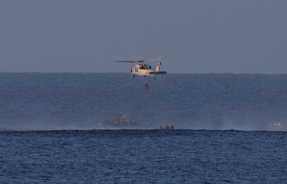 Een helikopter pikt een van de vier astronauten op om de crew over te brengen naar het grotere marineschip.