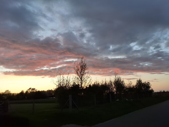 De ondergaande zon kleurde de wolken roze in Rekkem.