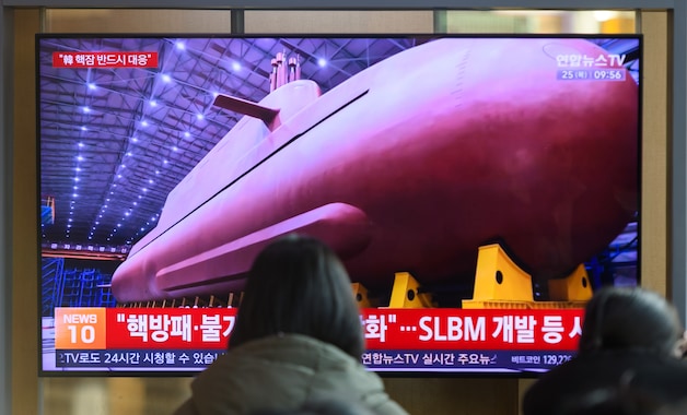 Zuid-Koreanen kijken naar beelden van de Noord-Koreaanse leider Kim Jong Un die een productielocatie onthult van een nucleair aangedreven strategische geleide-raketonderzeeër van 8.700 ton