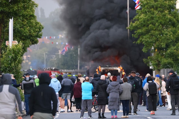 People watch as a vehicle burns out in north Belfast. (09/06/26)