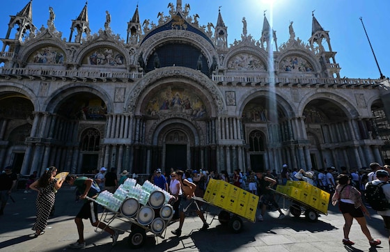 Des ouvriers transportent des chariots remplis de bouteilles d'eau à Venise. (27/06/26)