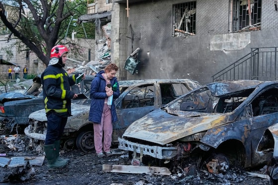 Een vrouw bekijkt de schade aan haar auto na de aanvallen op Kiev.
