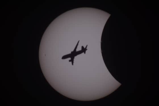 Tijdens de gedeeltelijke zonsverduistering vloog er een vliegtuig voorbij.