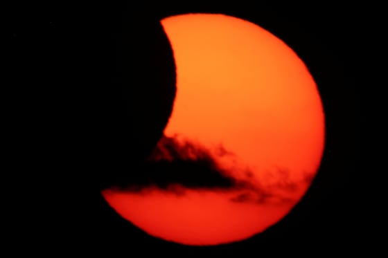 Een wolk trekt voorbij terwijl de maan de zon gedeeltelijk bedekt na een totale zonsverduistering vanuit Arija, Spanje.