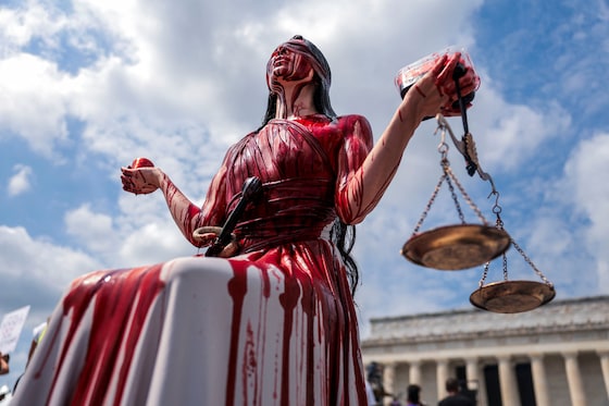 Een vrouw beeldt Vrouw Justitia uit, bedekt met nepbloed, tijdens de 'Defend the vote'-demonstratie in Washington D.C.