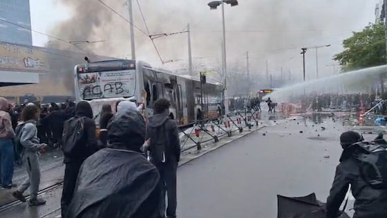 Relschoppers duwen de bus tot bij het waterkanon van de politie.