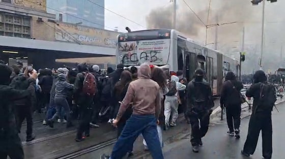 Relschoppers duwen de bus tot bij het waterkanon van de politie.