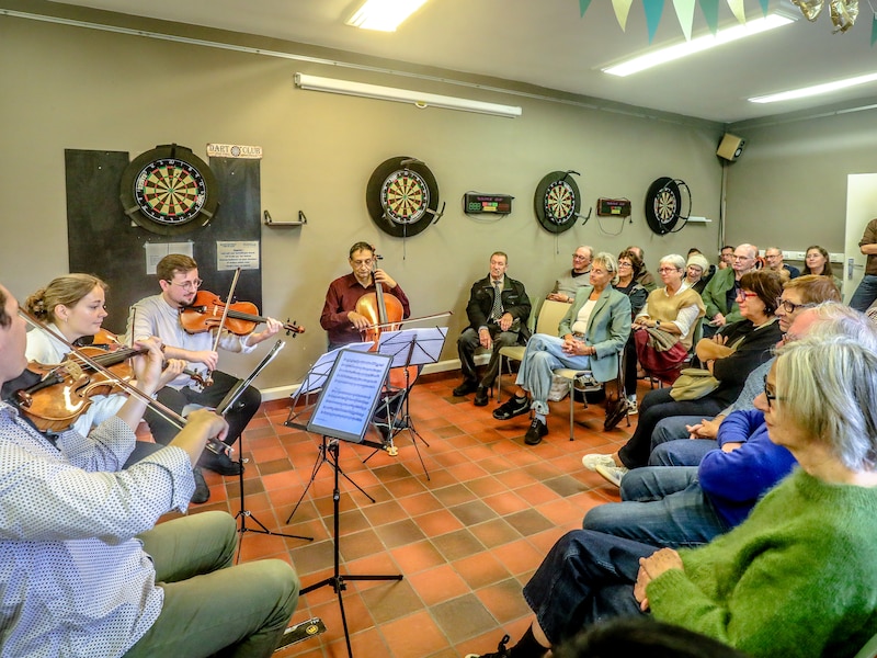 Toporkest brengt klassieke muziek (tussen de dartsborden) tot bij Bruggelingen die er zelf niet naartoe kunnen