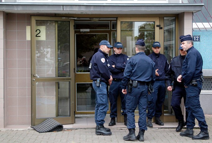 Enkele Franse agenten wachten aan de ingang van een gebouw waar vermoedelijke terroristen wonen.