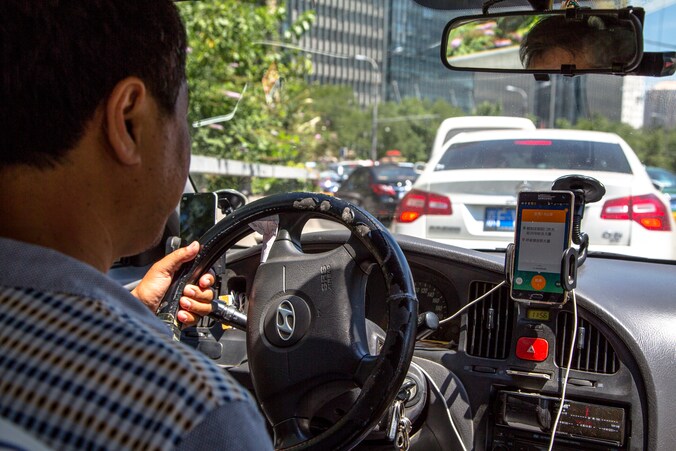 Een taxichauffeur die in Peking de app van Didi gebruikt.