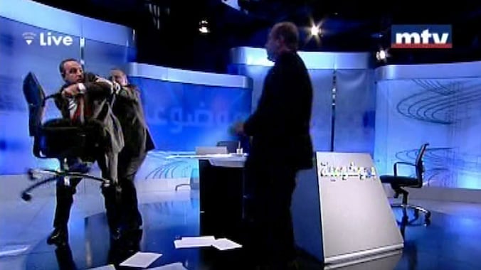 Shukr (links) wil een stoel gooien naar Alloush. De talkshowhost moet hem tegenhouden.