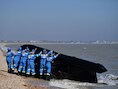 Leden van de kustwacht in Engeland halen een boot uit het water waarmee migranten het Kanaal van Frankrijk naar Engeland probeerden over te steken.