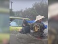 Op de beelden is te zien hoe een groep mannen – die tot hun middel in het water staan – de oudere man van zijn ondergelopen auto wegdragen. 