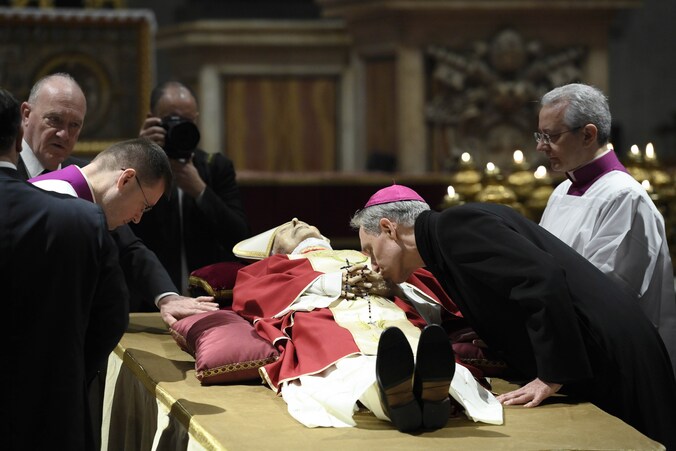 Enkele hoogwaardigheidsbekleders van Vaticaanstad nemen afscheid van de grijsgrauw opgebaarde Benedictus XVI.