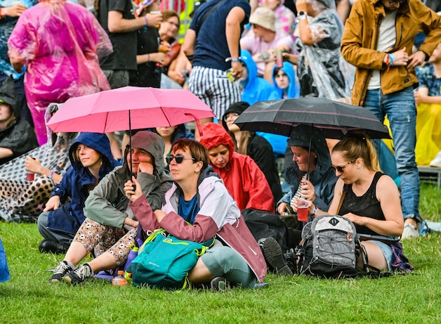Verschillende festivalgangers zochten eveneens beschutting onder paraplu’s.