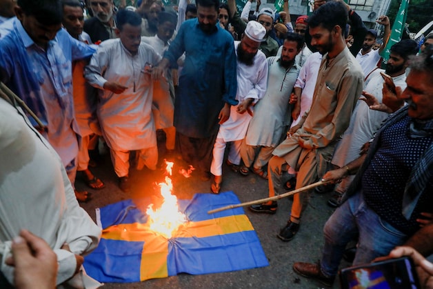 Aanhangers van de Tehreek-e-Labbaik Pakistan, een religieuze en politieke partij, verbranden een Zweedse vlag tijdens een protest tegen de ontheiliging van de Koran buiten een moskee in Stockholm, in Karachi, Pakistan, 7 juli 2023. 