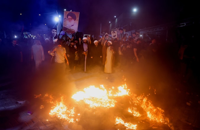 Aanhangers van de Iraakse sjiitische geestelijke Moqtada al-Sadr verbranden een holebi-vlag tijdens een protest tegen een man die een koran heeft verbrand buiten een moskee in Stockholm, in Bagdad, Irak, 12 juli 2023.