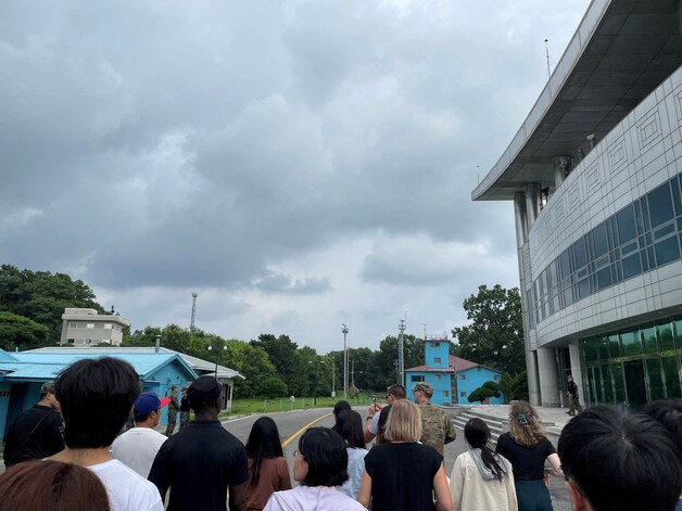 Travis King (met zwart shirt en zwarte pet op) liep kort na het nemen van deze foto de grens naar Noord-Korea (gemarkeerd door de gele lijn) over.