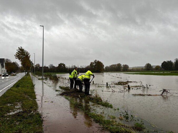 Gemeente-arbeiders proberen de Sint-Jansstraat vrij te houden van water.