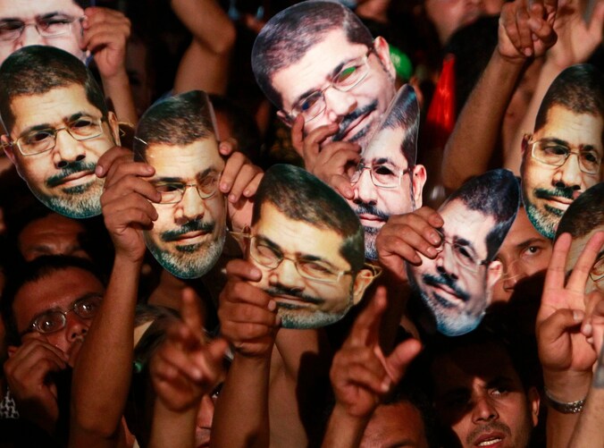 Moslimbroeders houden maskers van Mursi omhoog tijdens protest op het Rabaa Adawiya-plein.