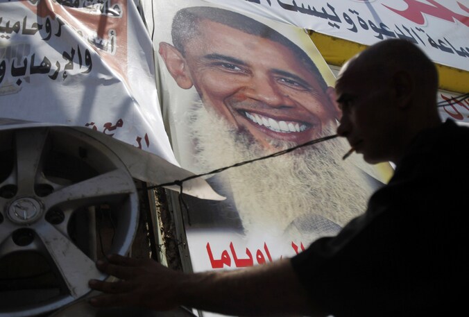 Een demonstrant hangt posters op van Obama met lange baard, om een statement te maken tegen de relatie tussen de VS en Egypte.