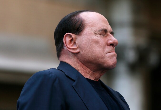 Silvio Berlusconi reageert op demonstranten bij het binnengaan van de rechtbank begin augustus, waar een zaak tegen hem diende vanwege belastingfraude.