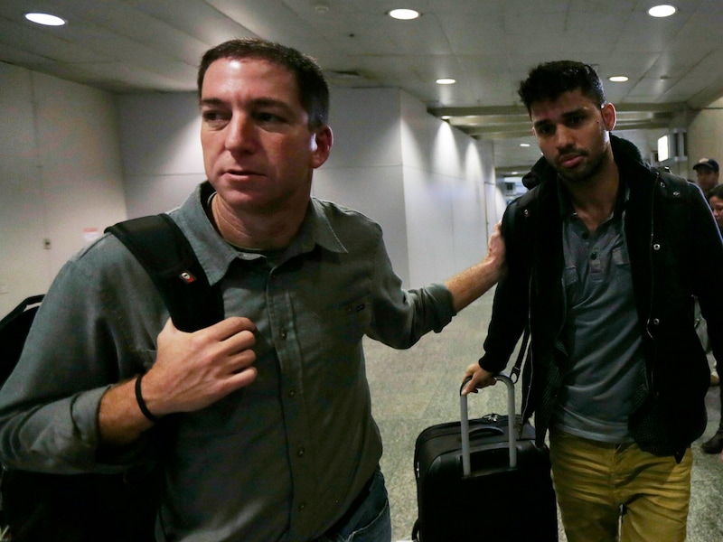 Guardian-journalist Glenn Greenwald (L) loopt met zijn partner David Miranda (R) op het vliegveld van Rio de Janeiro