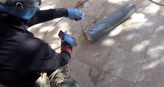 Screenshot van een YouTube-video waarop een inspecteur van de VN een bus onderzoekt die gifgas zou hebben bevat.