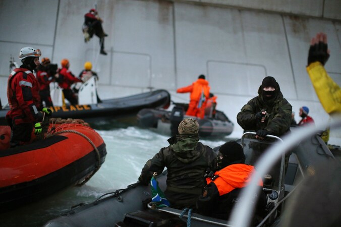 Een lid van de Russische kustwacht richt een geweer op een lid van Greenpeace.