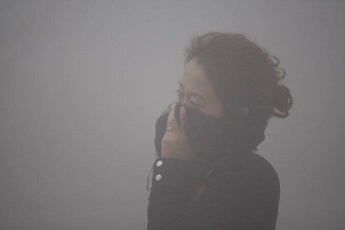 Een Chinese vrouw bedekt op dit archiefbeeld van 21 oktober 2013, haar mond tegen de smog in haar stad Harbin.