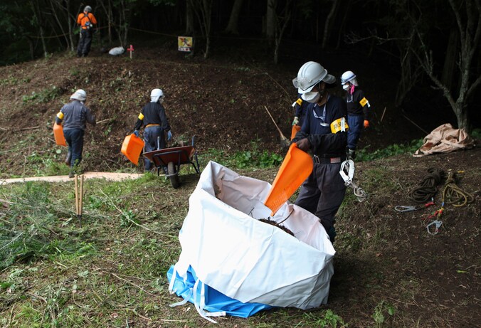 Arbeiders verwijderen besmette grond en bladeren in Fukushima. Volgens de Japanse wet mogen jongeren onder 18 niet werken in radioactieve gebieden.