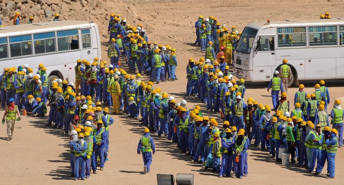 Arbeiders, die de WK-stadions bouwen in Qatar, verzamelen zich aan bussen.