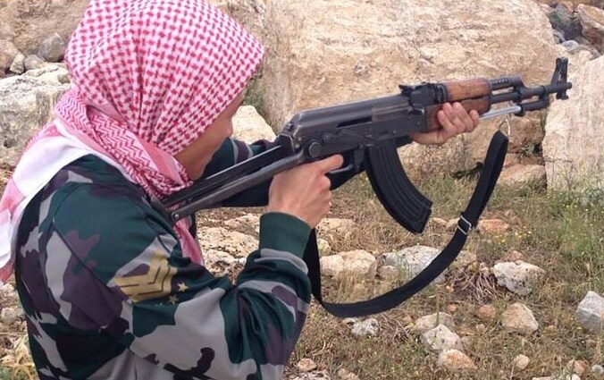 Een buitenlandse strijder, naar eigen zeggen afkomstig uit Denemarken, poseert voor een foto in een trainingskamp van het rebellenleger tussen Idlib en Aleppo, vorig jaar mei.