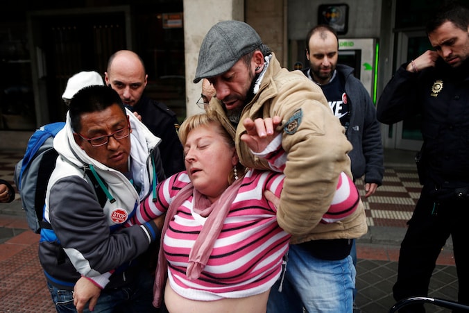 Een Madrileense vrouw die haar huis werd uitgezet wordt geholpen nadat ze een paniekaanval kreeg tijdens een protestactie.