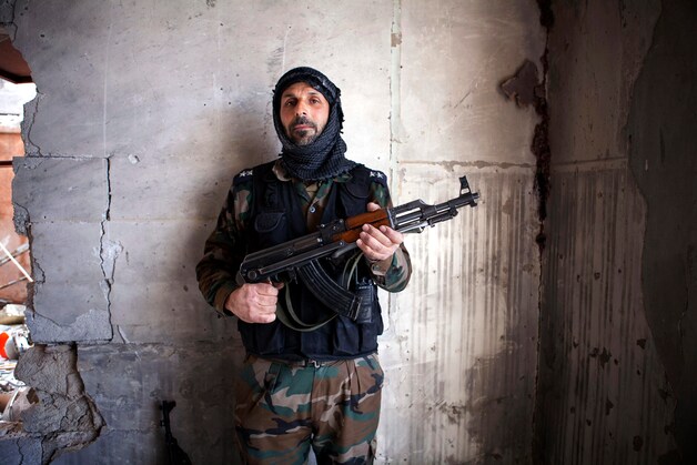 Een strijder van het Vrije Syrische Leger poseert met wapen in Saif Al Dawla.