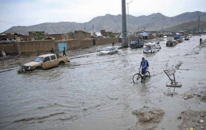 Een Afghaanse jongere rijdt op zijn fiets door de overstroomde straten van Kabul.