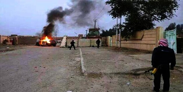 Een man staart naar een uitgebrande auto in Mosul.