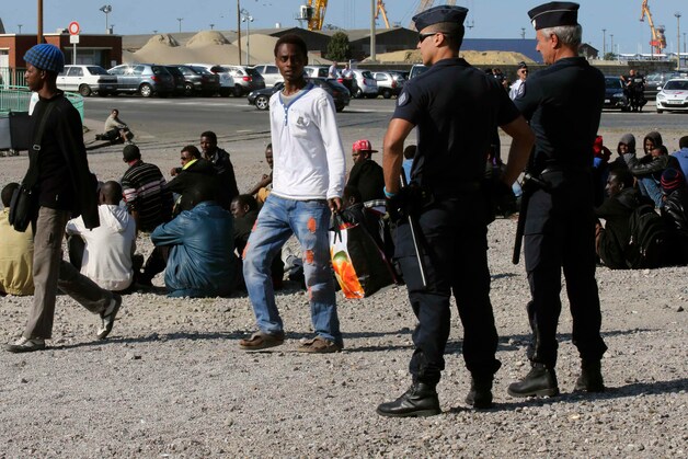 De Franse oproerpolitie bewaakt migranten die op hun dagelijkse voedselbedeling wachten in het centrum van Calais.