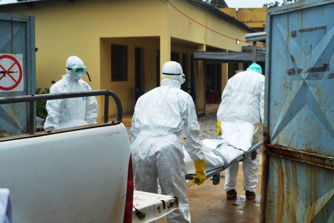 Gezondheidswerkers dragen het lichaam van een ebolaslachtoffer naar een geïmproviseerd ziekenhuis.