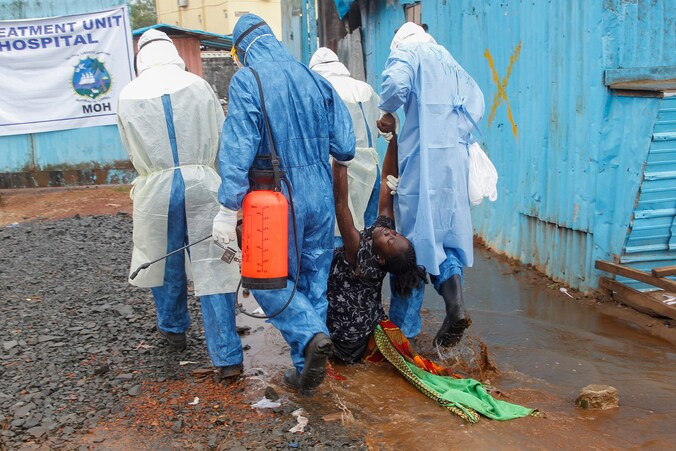 Een vrouw die vermoedelijk lijdt aan het ebolavirus wordt door gezondheidsmedewerkers naar een behandelcentrum in Liberia gebracht.